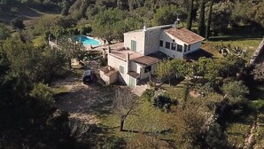 Ein Haus mit Schwimmbecken, umgeben von Bäumen und Hügeln.
