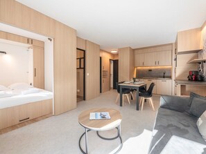 Une chambre d’hôtel de taille réduite, comprenant un lit, une petite table à manger, un canapé et une kitchenette.