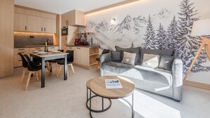 A modern living room with a sofa, a coffee table, and a dining area with chairs and a table.