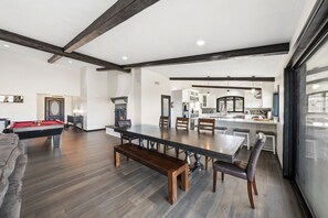 A spacious living area with a pool table, a dining table with chairs, and a kitchen area with modern appliances.
