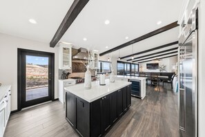 A modern kitchen with a central island, black cabinets, and a large window overlooking a desert landscape.