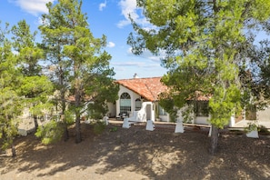 A building with a red-tiled roof, surrounded by trees and a clear sky.