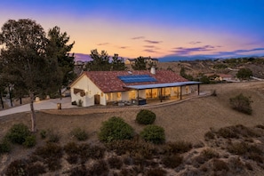 A house with a red-tiled roof, a covered patio, and solar panels.
