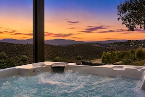 A hot tub with a view of a mountainous landscape during sunset.