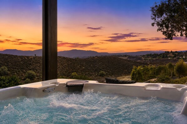 A hot tub with a view of a mountainous landscape during sunset. - Five bedroom hilltop view home with spa and fire pits (Temecula)