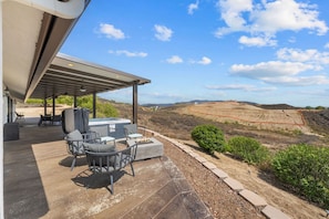 An outdoor patio with a pergola, seating, and a hot tub.