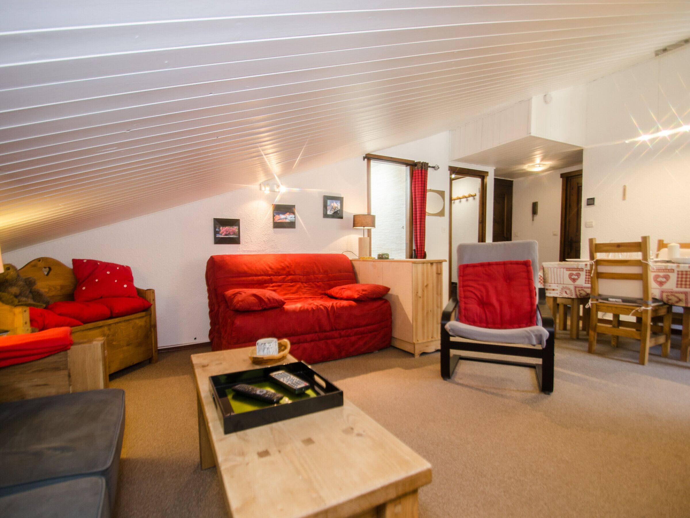 Ein gemütliches Wohnzimmer mit einem roten Sofa, einem Holztisch und einem Essbereich mit Tisch und Stühlen.
