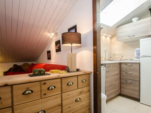 A bedroom with a wooden dresser, a red sofa, and a bedside table with a lamp. - Charming 4 pers apartment with parking and balcony in Chamonix (Chamonix-Mont-Blanc)