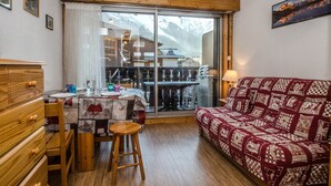 Una habitación acogedora con una mesa de comedor de madera, un sofá y vistas a montañas a través de un ventanal grande.