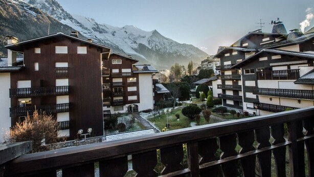 Un complejo turístico de montaña con edificios de estilo chalet, balcones y vistas a picos nevados.