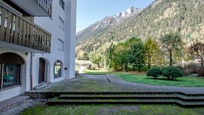 Un edificio con un patio, escalones que conducen a una puerta y una montaña al fondo.