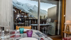 Comedor con una mesa para dos, vista a la montaña a través de un ventanal grande y detalles de madera.