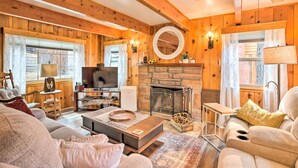 Ein gemütliches Wohnzimmer mit Kamin, Holzwänden, Fernseher und bequemen Sitzmöglichkeiten.