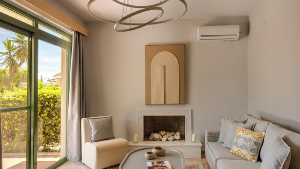 Una sala de estar con chimenea, un sofá, una mesa de centro y un ventanal con cortinas.