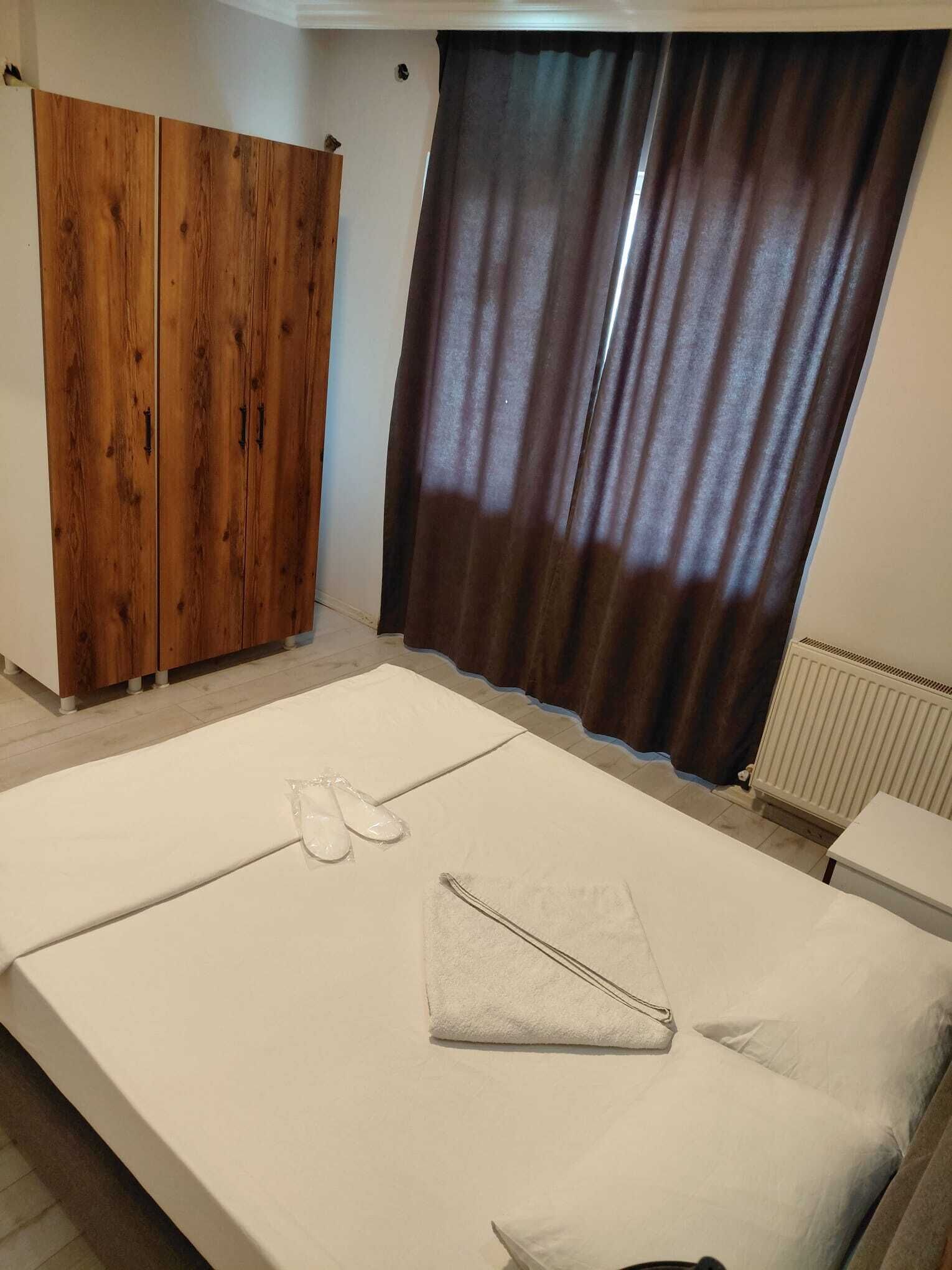 Quarto com cama, guarda-roupa de madeira e janela com cortinas.