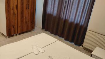 A bedroom with a bed, a wooden wardrobe, and a window with curtains.