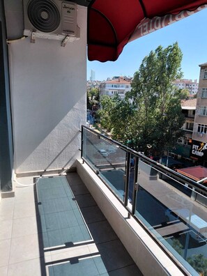 A balcony with a glass railing, a red awning, and a view of the cityscape. - ESTA123 APART (Ankara)