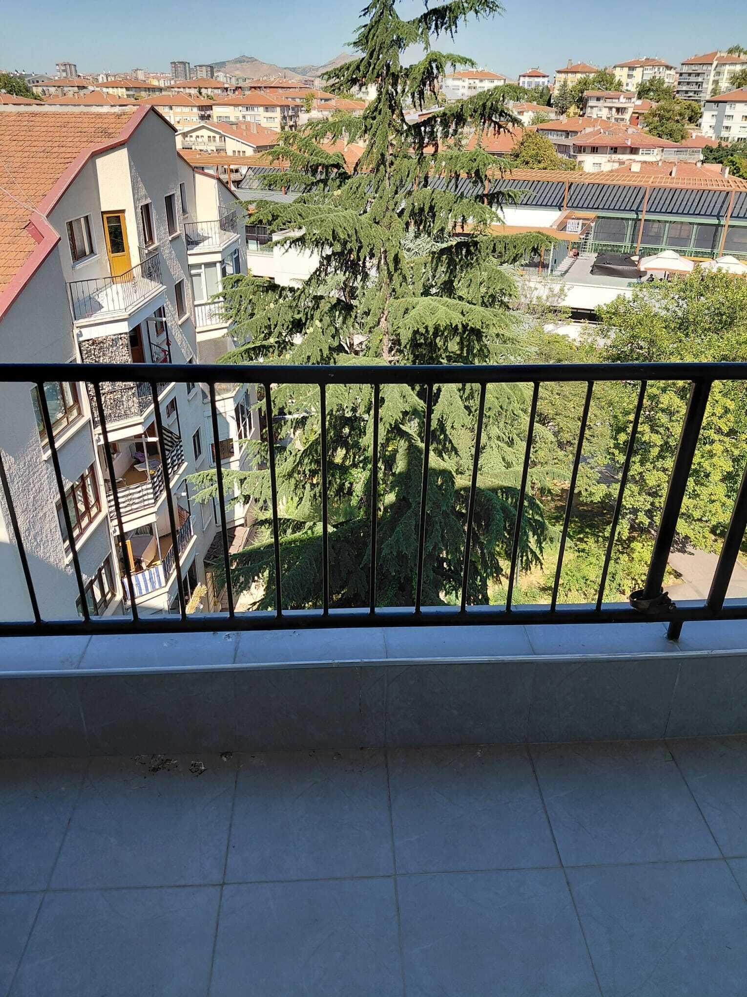 Un balcón con vista a una zona residencial, con edificios y árboles.