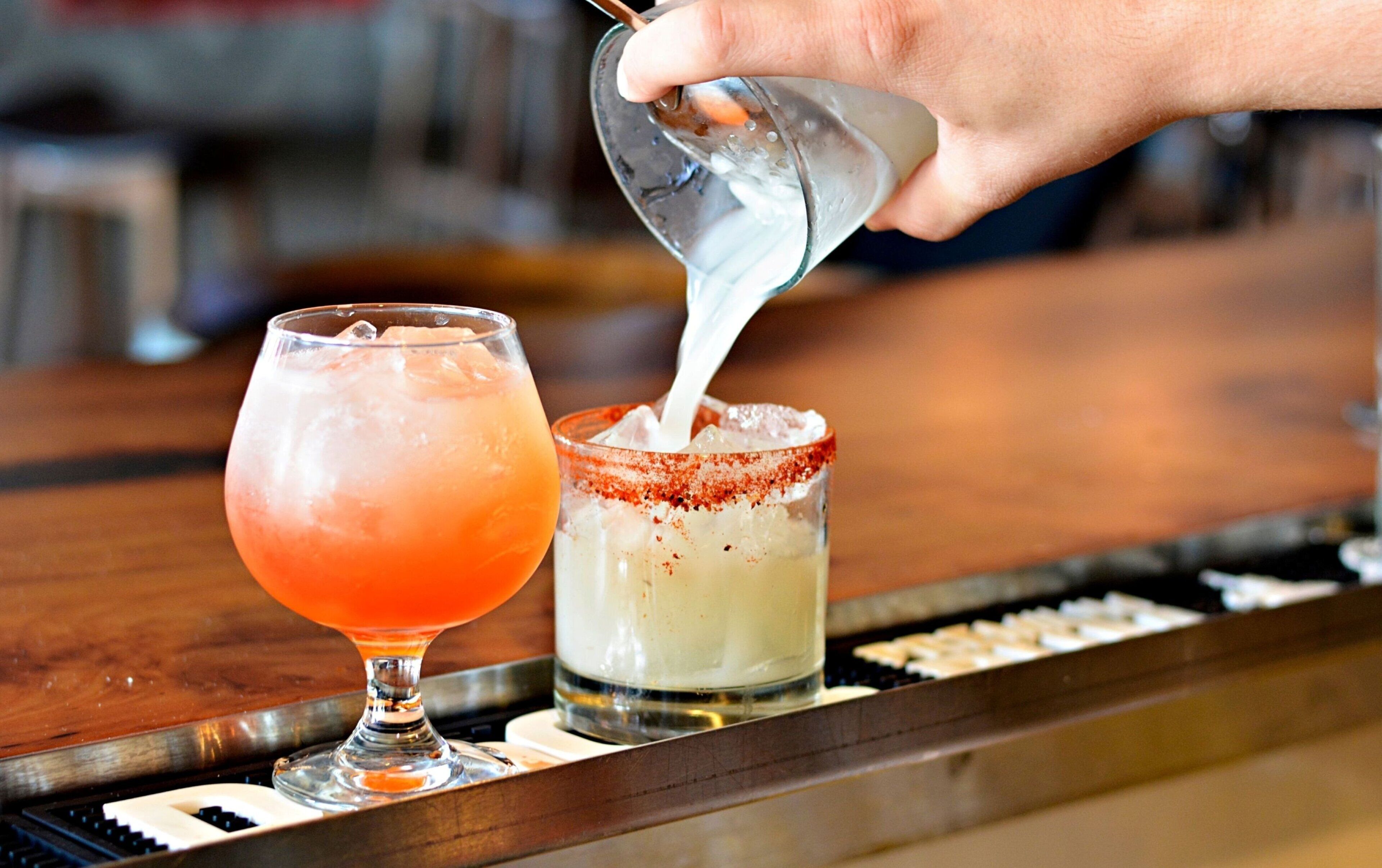 A bartender pouring a drink into a glass.