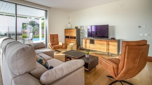 A modern living room with a sofa, armchairs, a coffee table, and a TV. - Amazing home in Dehesa de Campoamor (Dehesa de Campoamor)