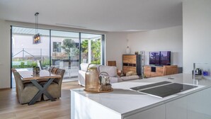 A modern kitchen with a central island, a dining area with a glass table, and a living space with a sofa and TV. - Amazing home in Dehesa de Campoamor (Dehesa de Campoamor)