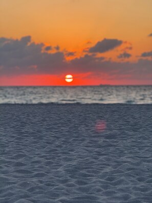 Een strand met een ondergaande zon op de achtergrond.