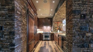 A narrow kitchen with stone walls and wooden cabinets.