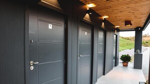 Una hilera de puertas grises oscuras con diseño moderno, techo de madera y una planta en maceta a la derecha.