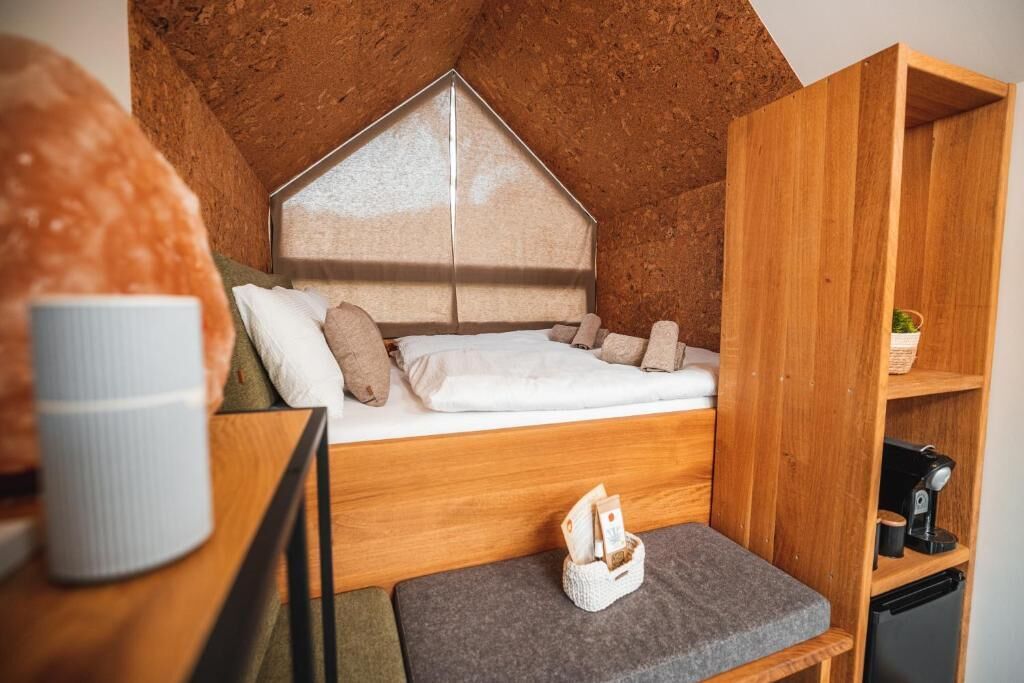 Ein kompakter, rustikaler Raum mit Schlafkoje, einer kleinen Sitzecke und einem Holzregal mit Kaffeemaschine.
