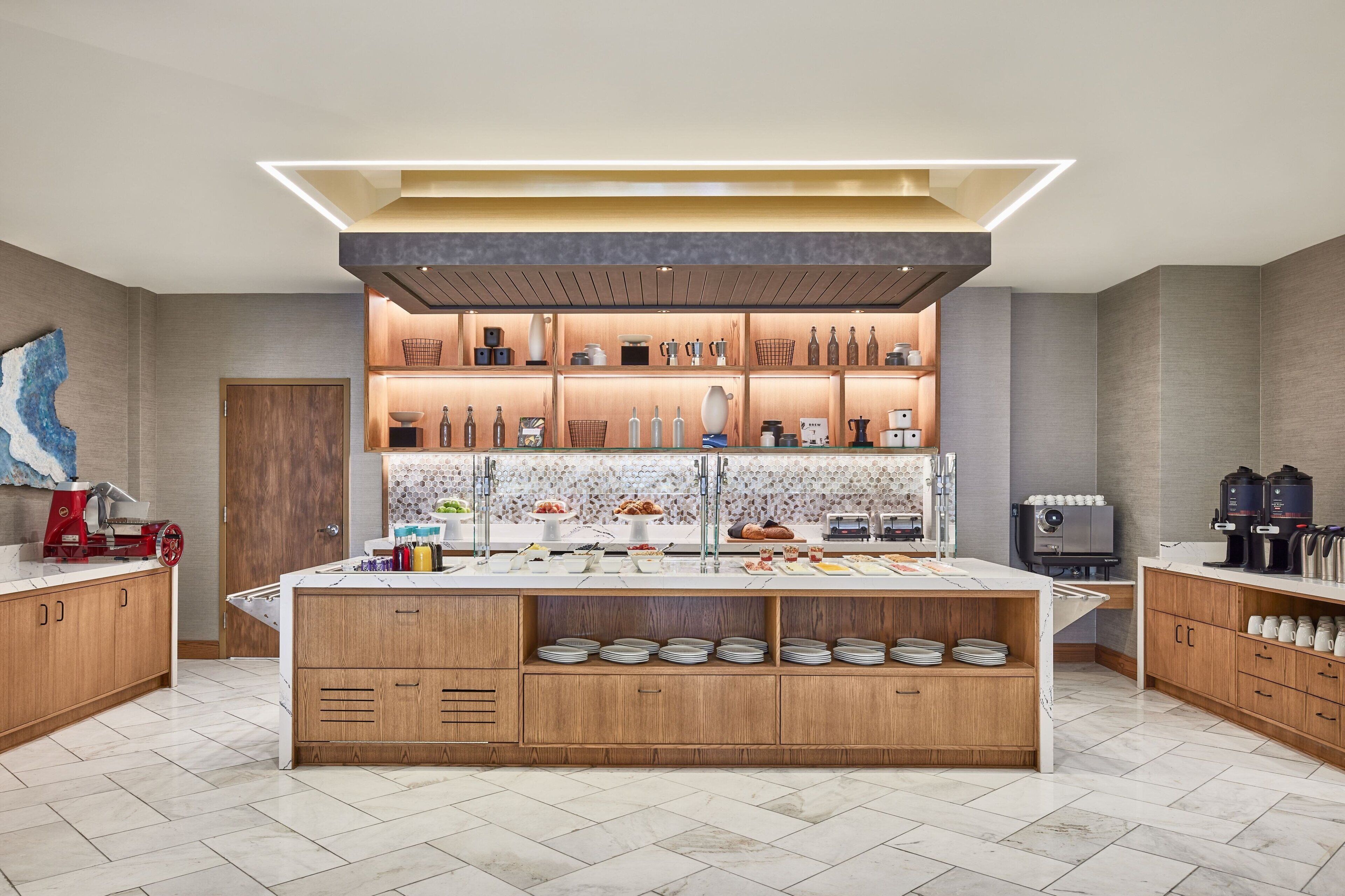 A modern kitchen with a central island, wooden cabinets, and a variety of appliances and utensils.