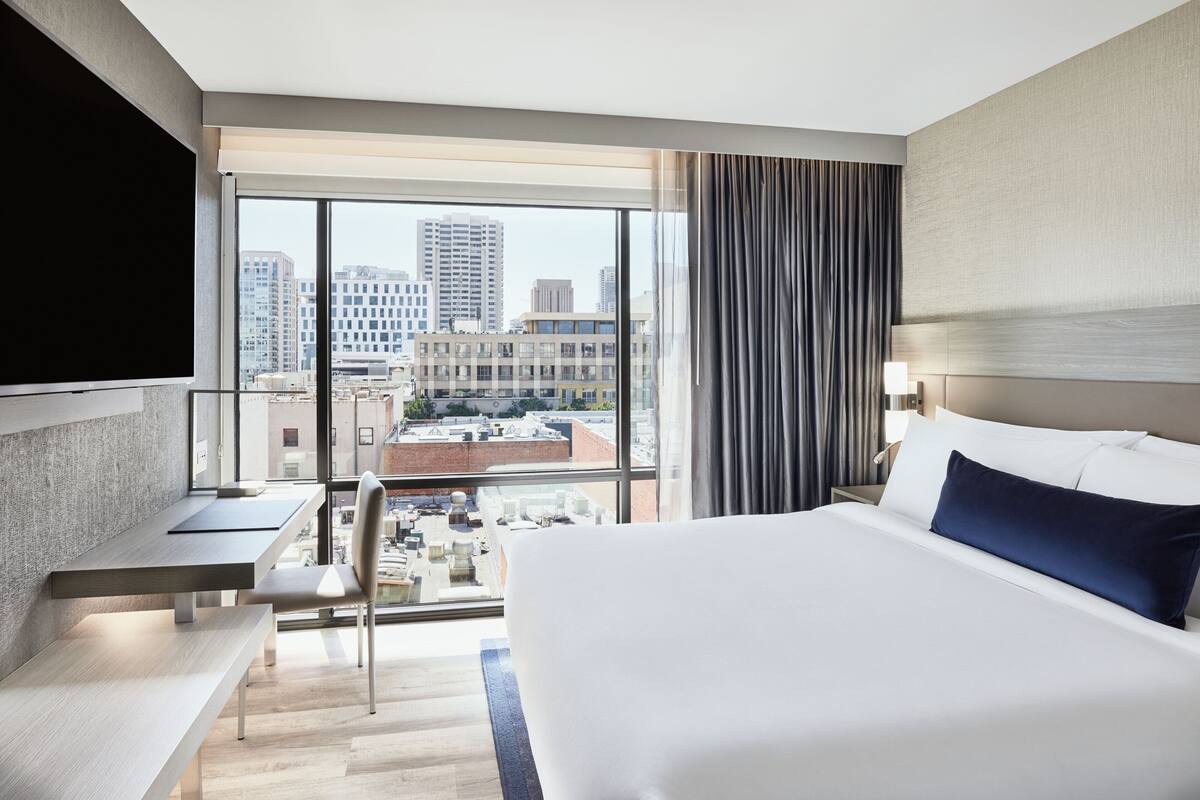 Ein Hotelzimmer mit einem großen Bett, einem Schreibtisch, einem Stuhl und einem Fernseher.