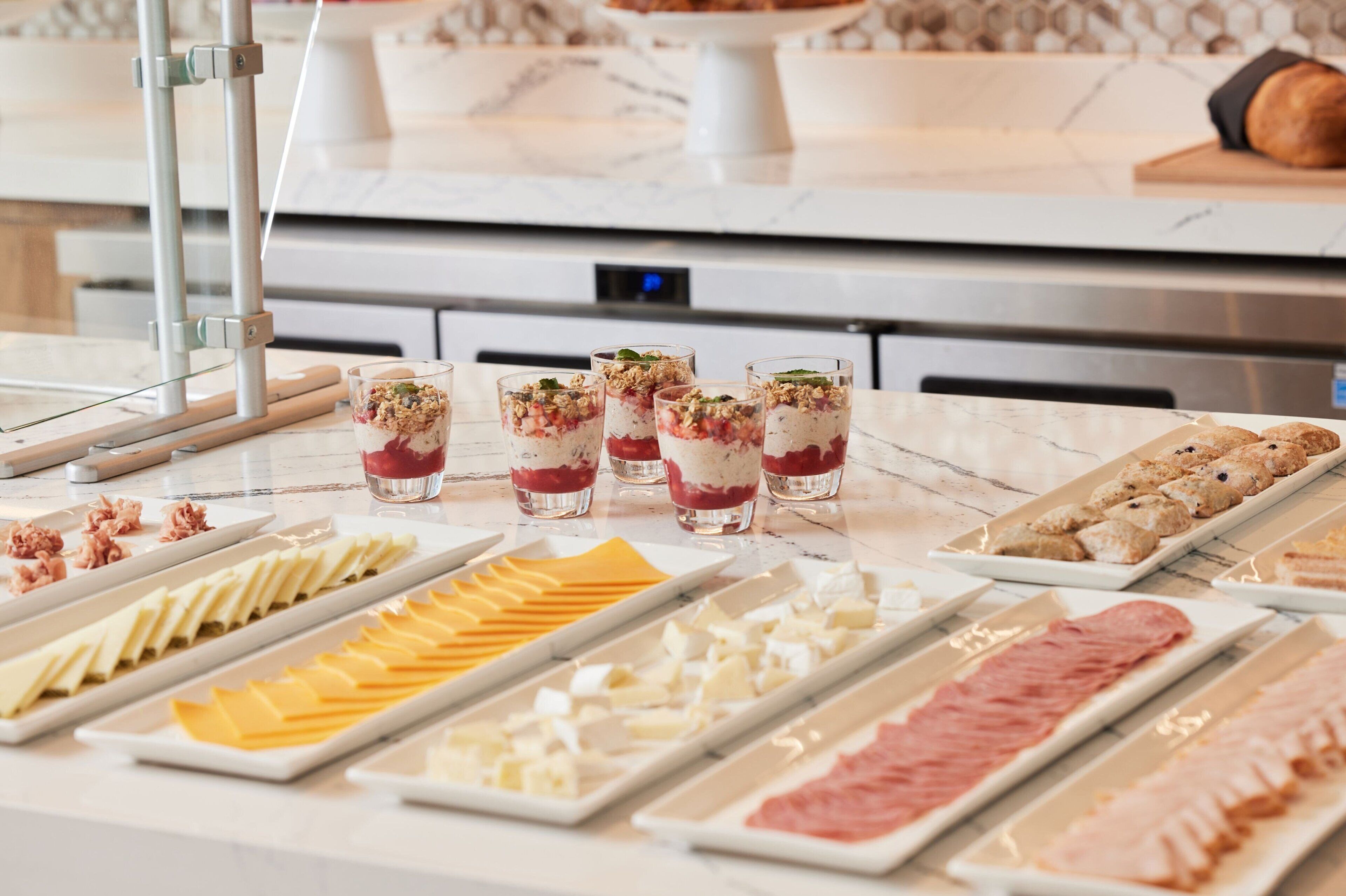 A buffet with various food items including meats, cheeses, and desserts.