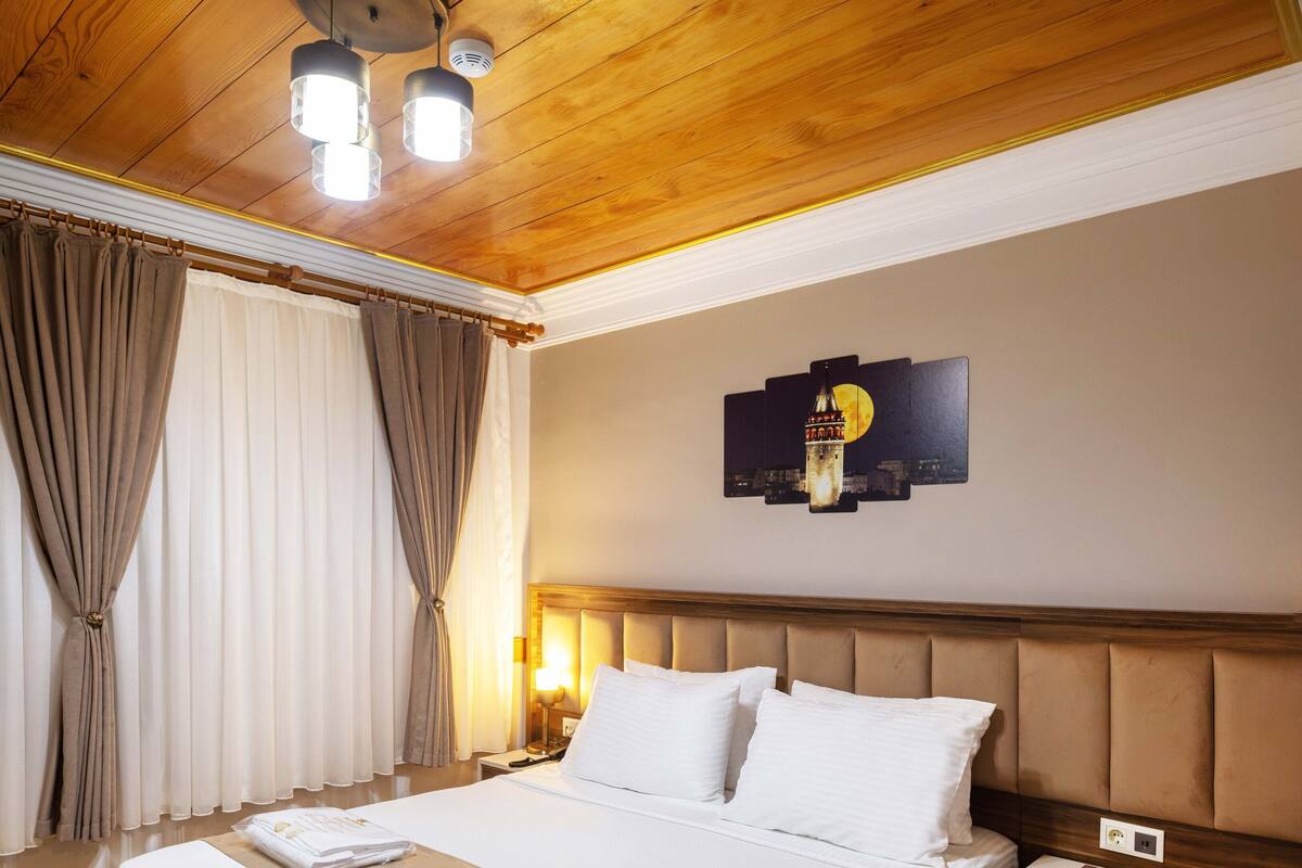 A neatly made bed with a headboard, a bedside table with a lamp, and a wall-mounted artwork.