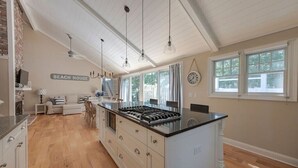 A kitchen with a central island, wooden flooring, and pendant lighting.