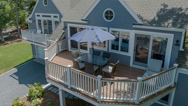 A two-story house with a deck, a covered patio, and a large window.