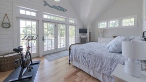 A bedroom with a bed, exercise bike, and a large window.