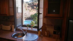 A kitchen with a large window, a sink, and wooden cabinets. - Casa do Adro-Passadiços do Paiva (Espiunca)