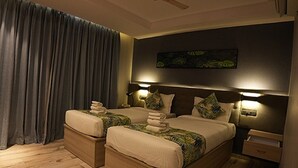 A double bed with a dark headboard, two bedside tables, and a large window with curtains. - Hotel Ocean Vista Bay (Visakhapatnam)