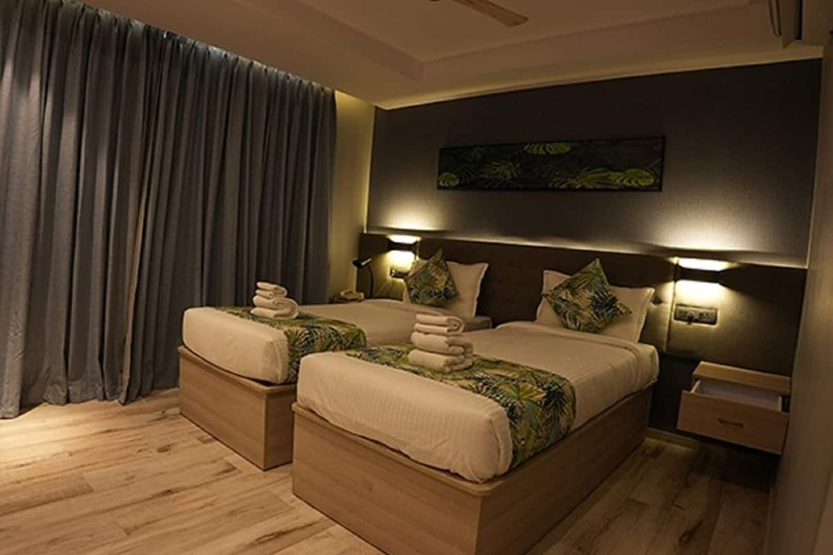 A double bed with a dark headboard, two bedside tables, and a large window with curtains.