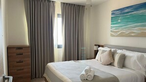 Ein Hotelzimmer mit einem Bett, einem Holzschrank und einem Bild mit Strandmotiv.