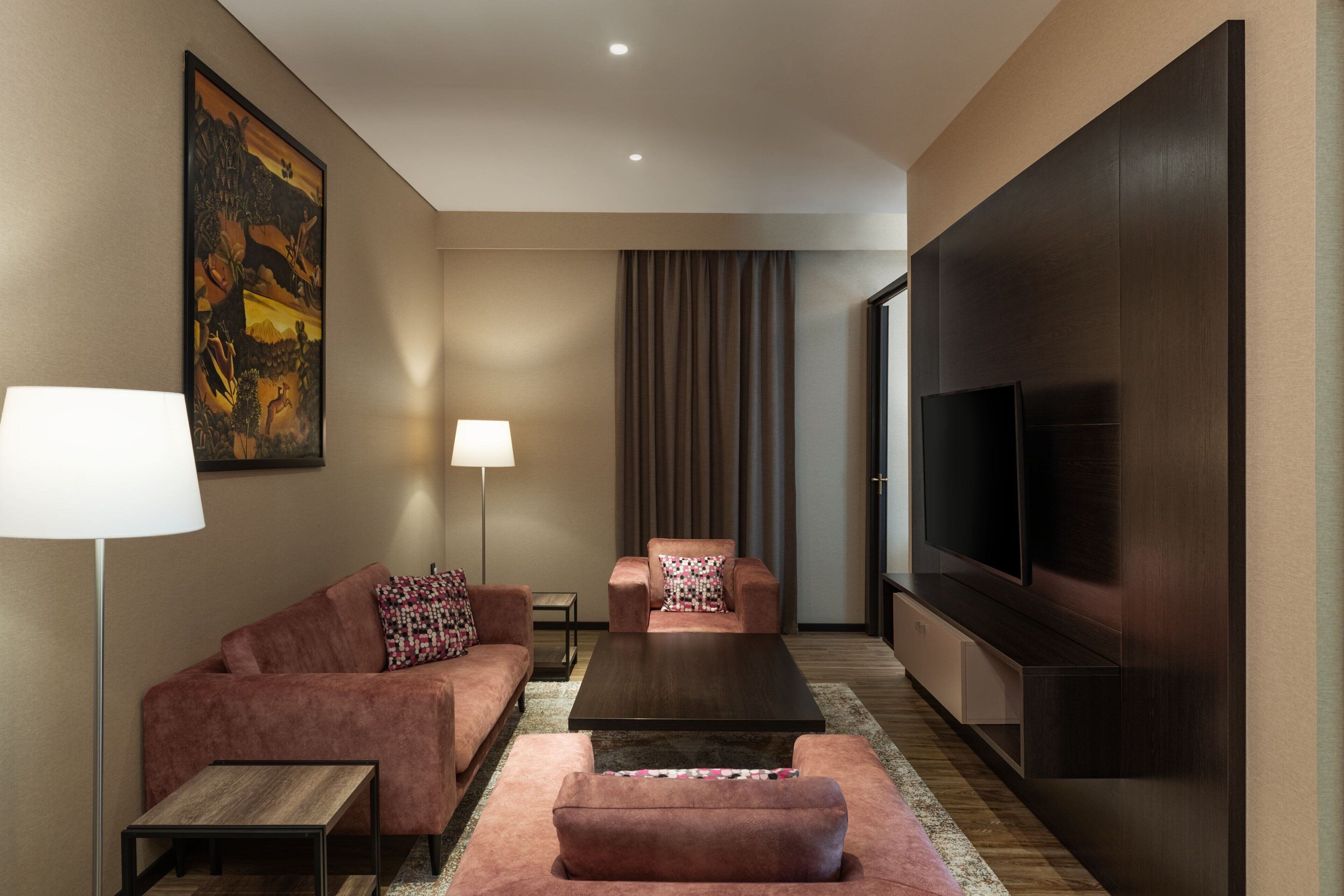 A modern living room with a sofa, armchair, coffee table, and a flat-screen TV.