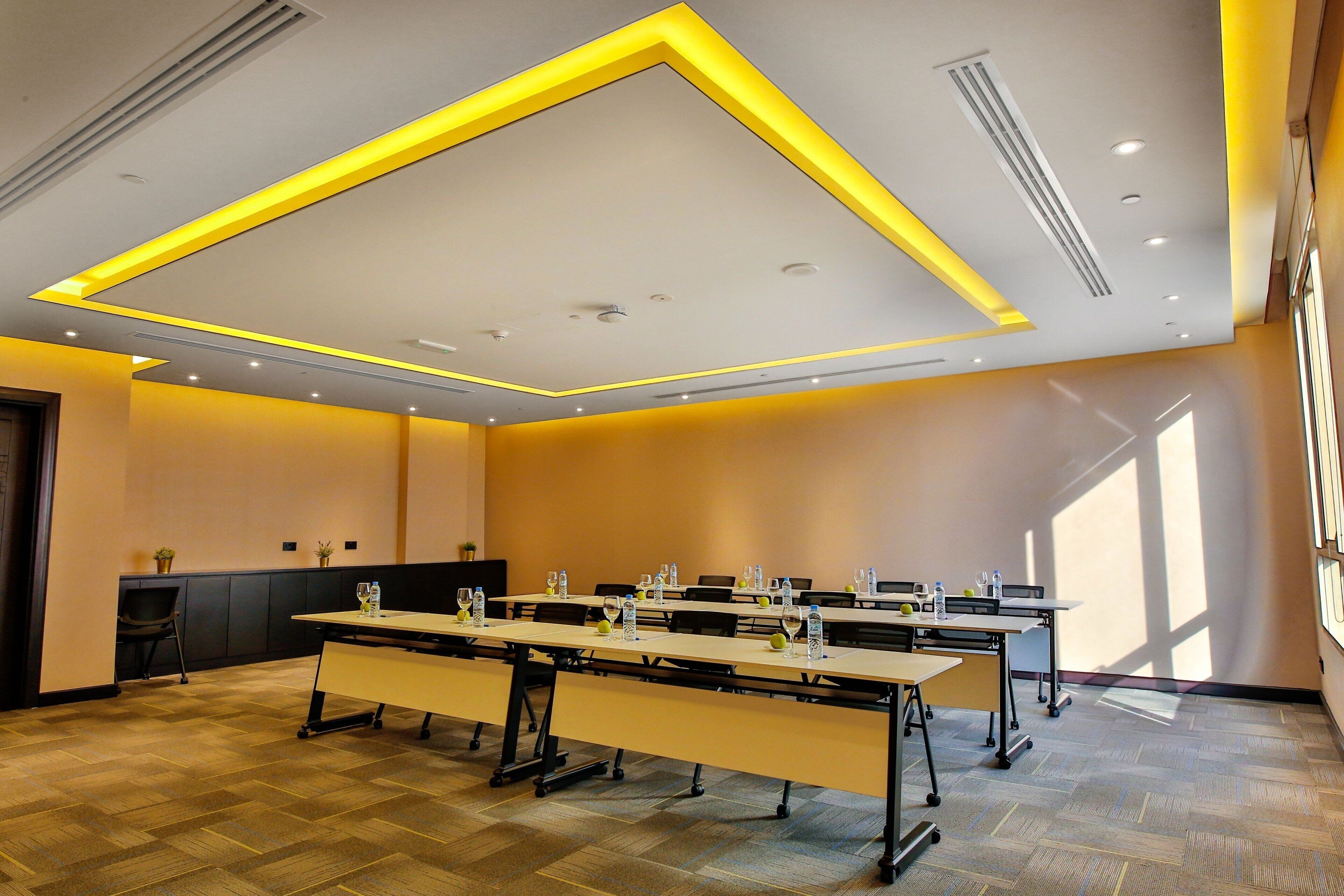 A conference room with a long table, chairs, and a ceiling with recessed lighting.