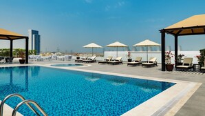 A rooftop pool with lounge chairs and umbrellas, surrounded by a cityscape. - Four Points by Sheraton Production City, Dubai (Dubai)