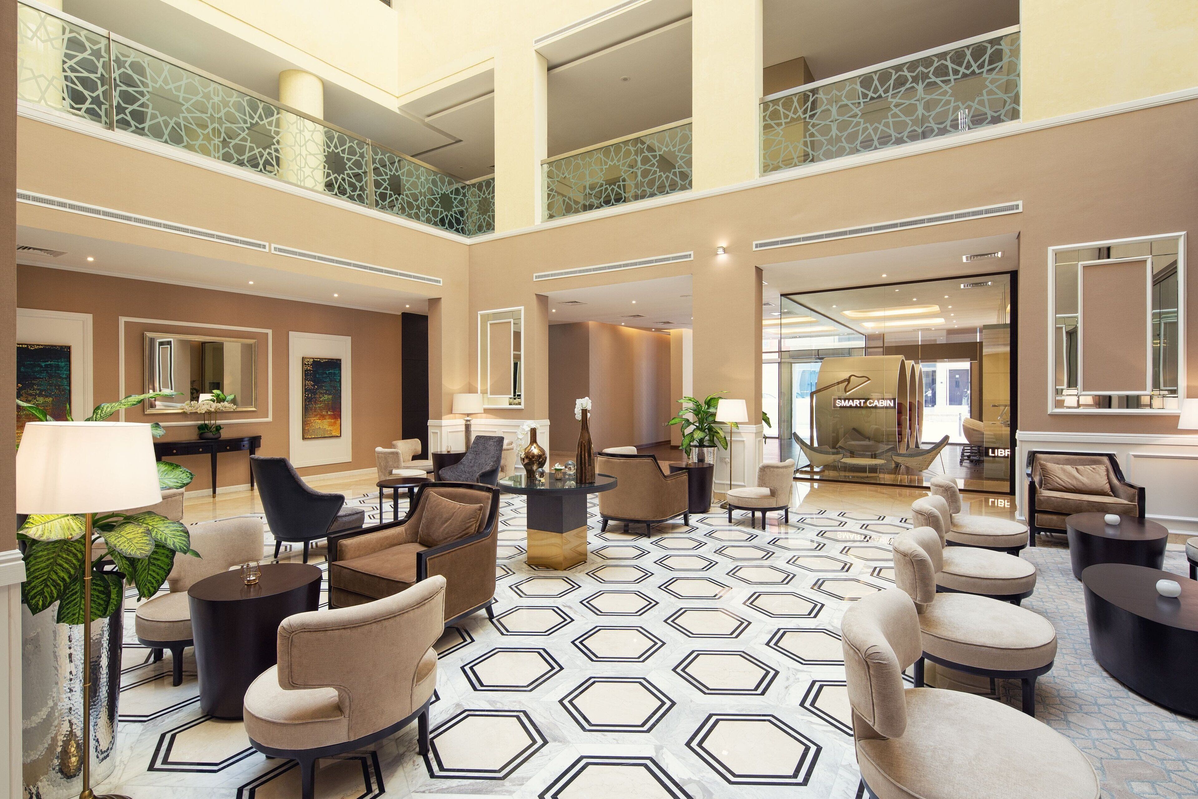 A spacious lobby with a geometric patterned floor, multiple seating areas, and a Smart Cabin sign visible in the background.