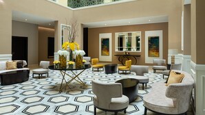 A spacious lobby with a high ceiling, geometric patterned floor, and a variety of seating options including sofas and armchairs. - Four Points by Sheraton Production City, Dubai (Dubai)