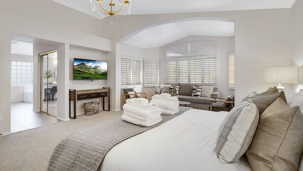 A spacious bedroom with a large bed, a TV mounted on the wall, and a desk with a chair. - Sweet Escape l Heated Pool l Luxury Living (Scottsdale)