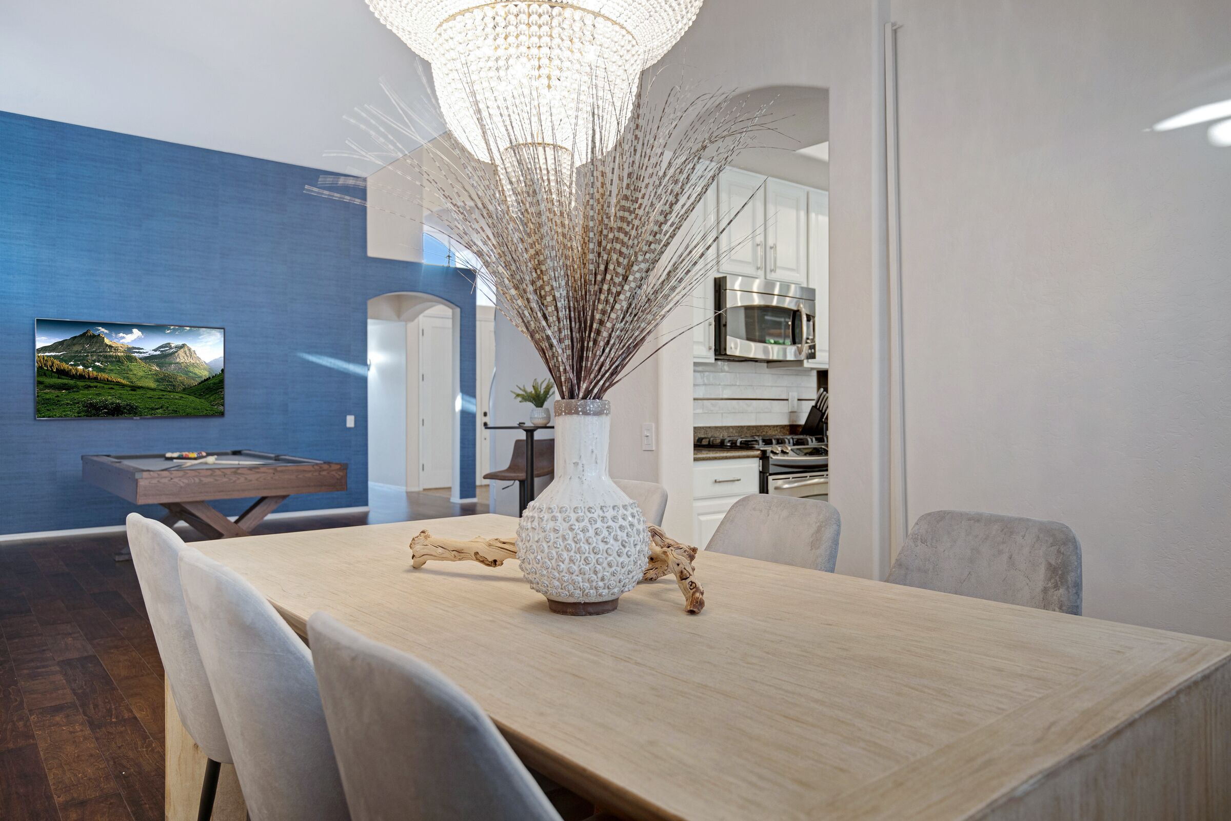 A dining area with a wooden table, chairs, a decorative vase, and a chandelier.