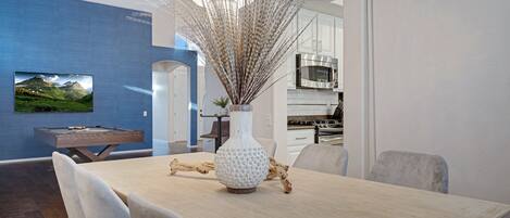 A dining area with a wooden table, chairs, a decorative vase, and a chandelier.
