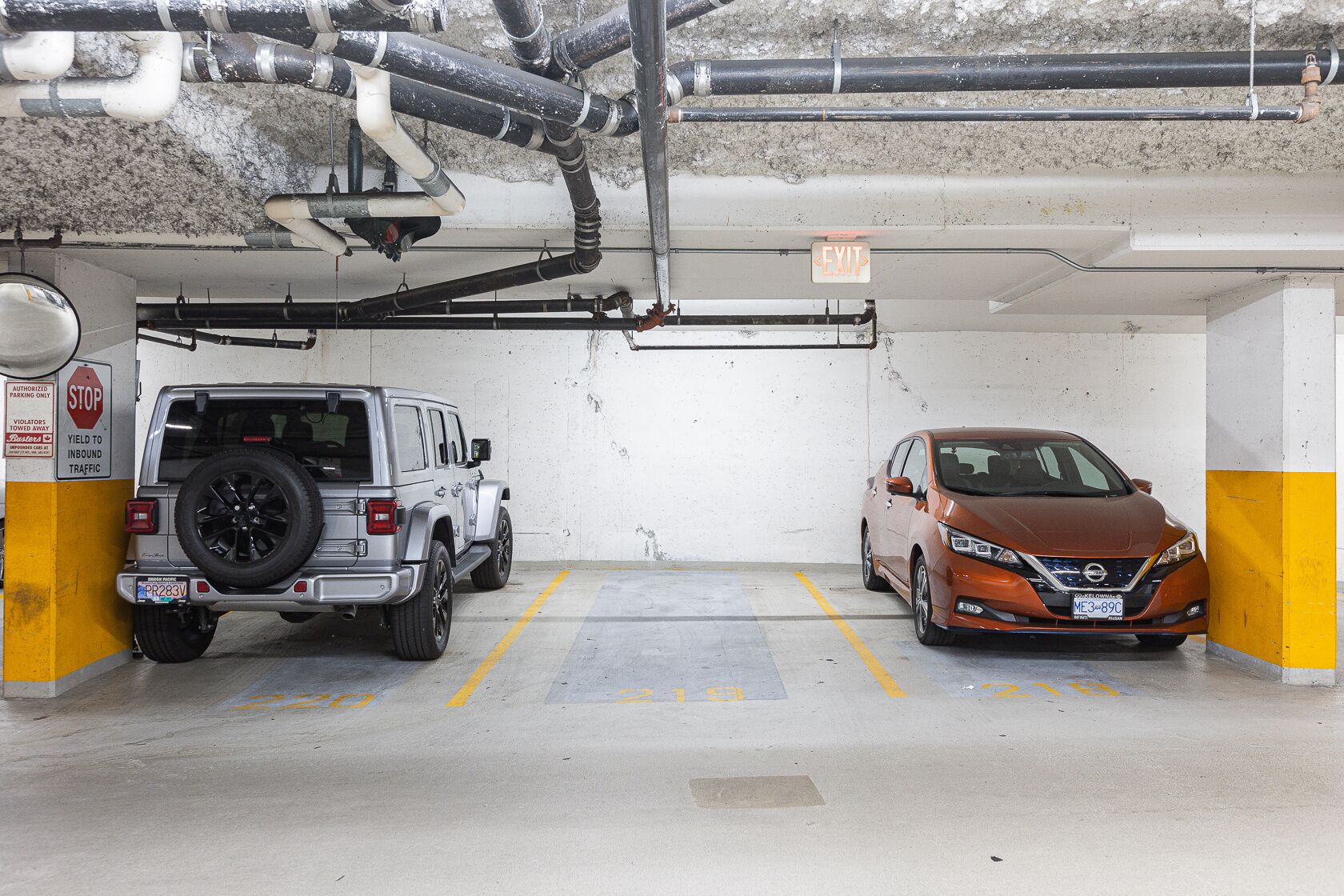 A parking garage with two cars parked in adjacent spaces.