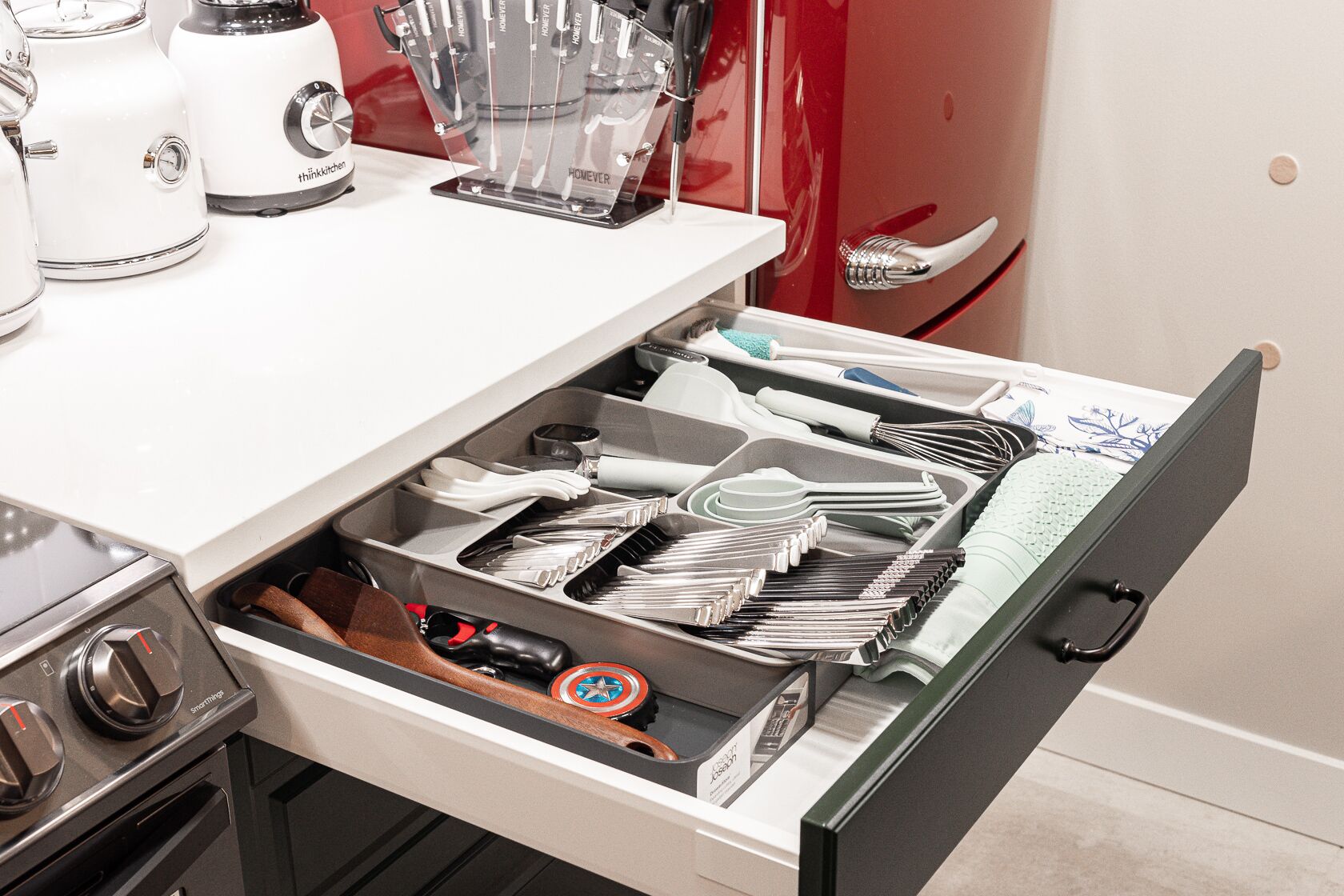 A kitchen drawer with utensils and a coffee maker.